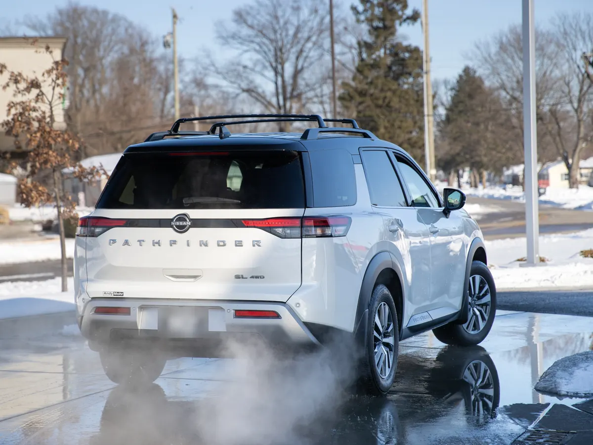 A freshly washed white SUV pulling out of a Kopetsky Auto Wash past snowbanks