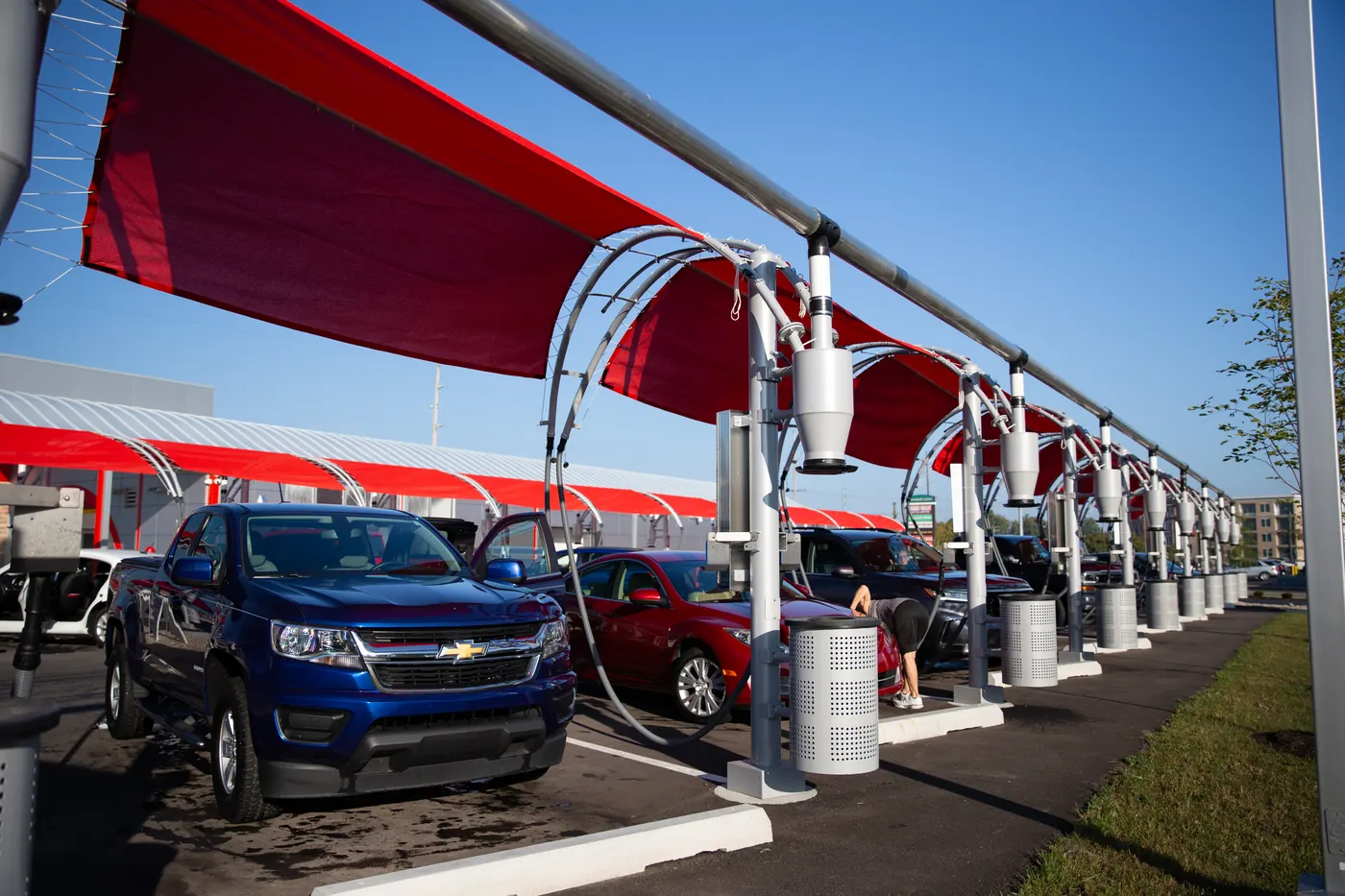 Customers using the free vacuums under the red canopies at Kopetsky Auto Wash